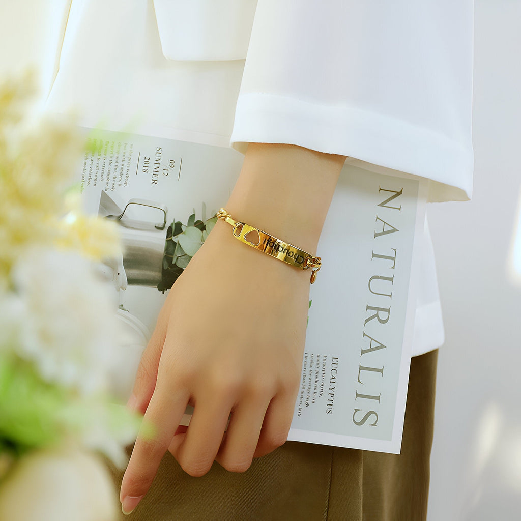 Bracelet gourmette en acier inoxydable or avec pendentif cœur, porté au poignet femme.