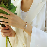 Bracelet gourmette en acier inoxydable or rosé avec pendentif cœur porté sur poignet féminin.