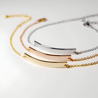 Or jaune, or rosé et argent, chaînes fines et barre lisse incurvée.
