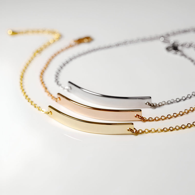 Or jaune, or rosé et argent, chaînes fines et barre lisse incurvée.