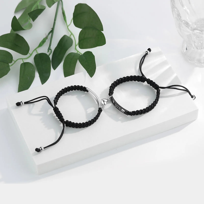 Paire de bracelets gourmette en acier inoxydable, l'un argenté, l'autre noir, avec cordon tressé réglable.