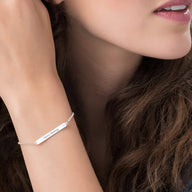 Bracelet gourmette en argent sterling avec plaque fine et chaîne délicate sur poignet féminin.