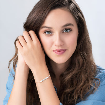 Bracelet gourmette en argent sterling fin orné d'oxydes de zirconium porté sur poignet féminin.