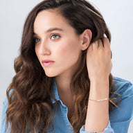 Bracelet gourmette en argent sterling avec zircons, porté au poignet d’une femme aux cheveux bruns, style épuré.