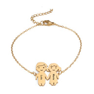 Bracelet en acier inoxydable doré avec deux pendentifs personnages personnalisés, chaîne fine et fermoir mousqueton.