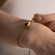 Bracelet or en acier inoxydable avec pierre ovale de lapis lazuli bleu profond sur chaîne fine tressée.