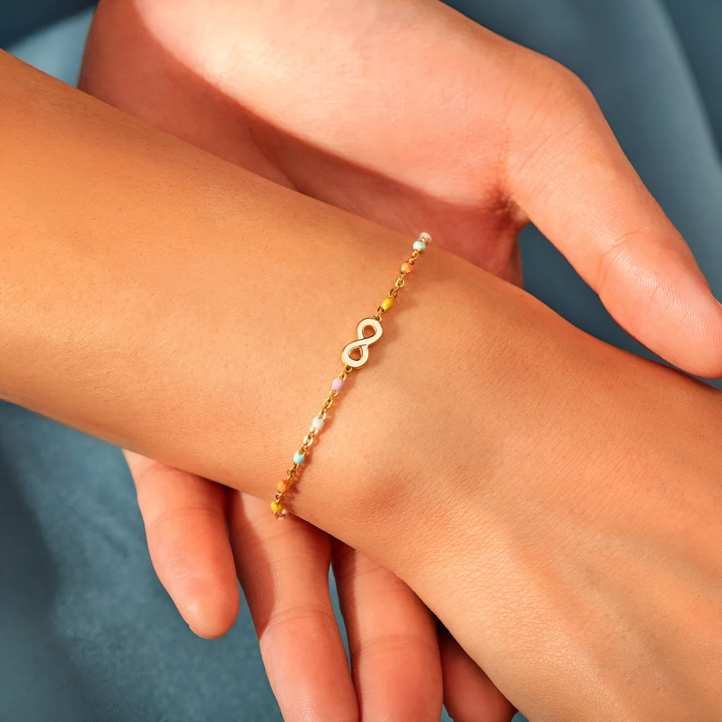Bracelet fin infini en argent sterling doré avec chaîne délicate porté au poignet féminin.