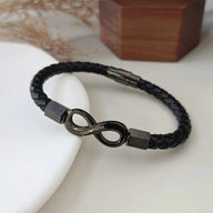 Bracelet en cuir tressé noir avec ornement infini en métal gris foncé brillant et fermoir magnétique gris anthracite.