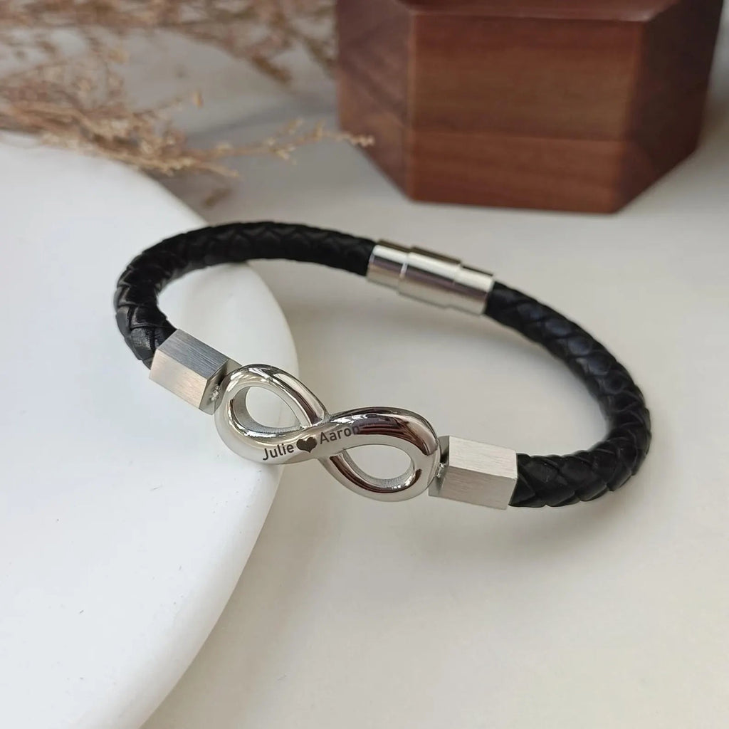 Bracelet en cuir noir tressé avec ornement infini en métal argenté et fermoir magnétique assorti.
