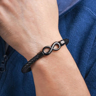 Bracelet en cuir noir tressé avec ornement infini en métal argenté élégant.