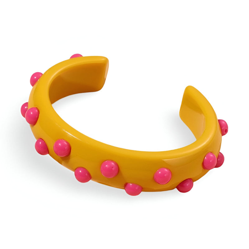 Bracelet jonc jaune en résine avec breloques rondes roses décoratives.
