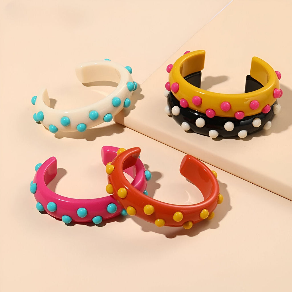 Bracelets joncs en résine avec breloques rondes colorées, modèles rose, orange, blanc et noir.