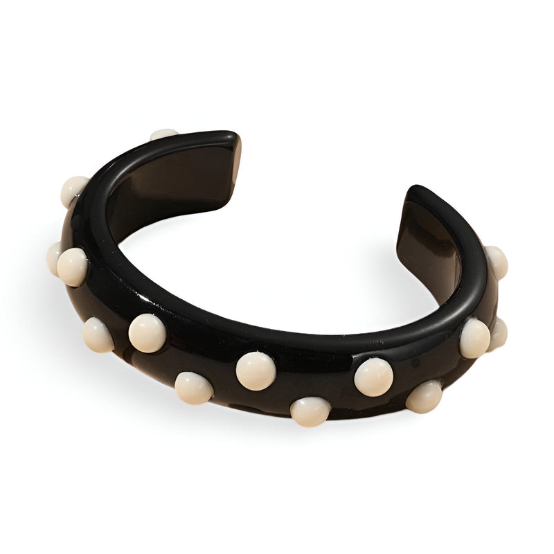 Bracelet jonc noir en résine avec petites breloques rondes blanches réparties uniformément.