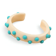 Bracelet jonc en résine crème avec breloques rondes turquoise réparties uniformément.