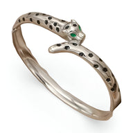 Bracelet jonc argent en forme de léopard aux yeux verts incrustés et taches noires détaillées.