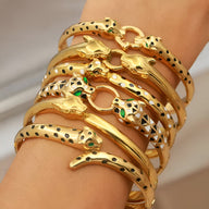 Bracelets joncs dorés et argentés en forme de tête de léopard avec yeux verts, design effilé et taches noires.