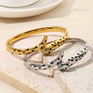 Bracelet jonc en or jaune et argent avec motif léopard et yeux verts, style élégant pour femme.