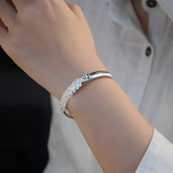 Bracelet jonc argent sterling avec motif paon détaillé porté au poignet féminin.