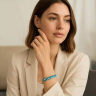 Bracelet jonc bleu ciel en cuivre plaqué or à motif fleuri scintillant porté au poignet féminin.