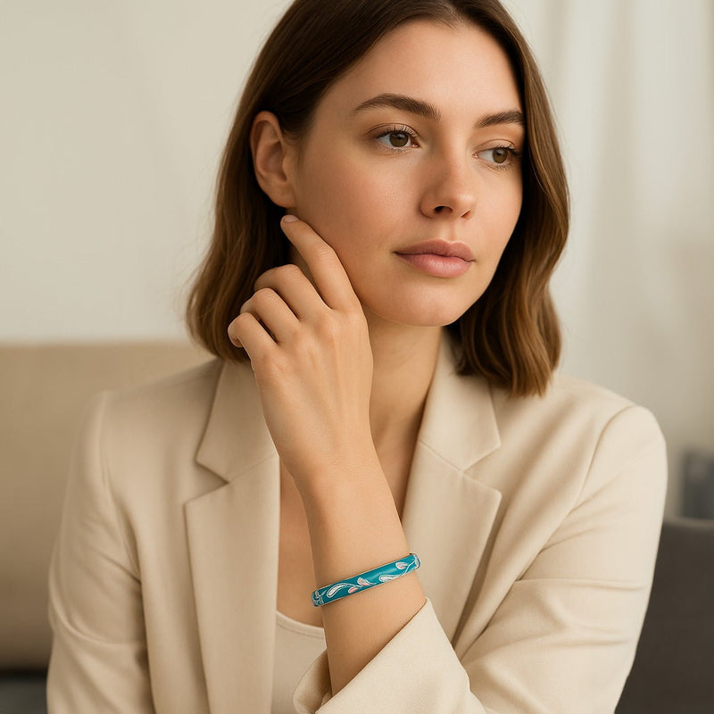 Bracelet jonc bleu ciel en cuivre plaqué or à motif fleuri scintillant porté au poignet féminin.