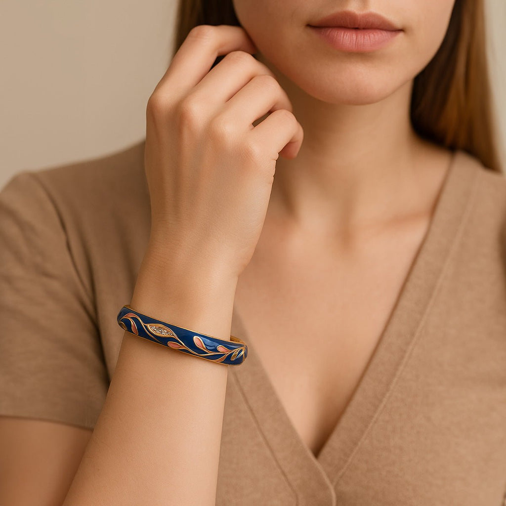 Bracelet jonc en cuivre plaqué or bleu foncé avec motifs floraux scintillants porté au poignet.