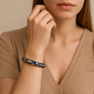 Bracelet jonc en cuivre plaqué or bleu foncé avec motifs floraux scintillants porté au poignet.