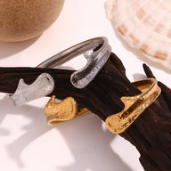 Bracelet jonc moderne en acier inoxydable, finitions argent et or texturées, design contemporain.