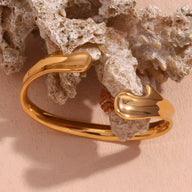 Bracelet jonc en acier inoxydable doré forme fluide et moderne finition brillante.