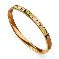 Bracelet jonc en métal doré avec émail vert clair, jaune et motifs floraux abstraits.