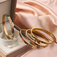 Bracelet jonc émaillé doré avec motifs colorés rouges, verts et noirs, style Caliesta pour femme, présenté dans un coffret.