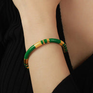 Bracelet jonc en titane vert avec détails dorés, modèle Bulie, porté au poignet féminin.