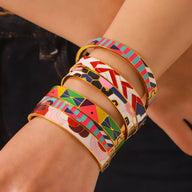 Bracelets joncs émaillés colorés aux motifs géométriques et abstraits sur bras féminin.