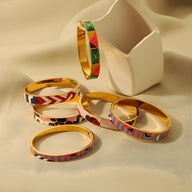 Set de six bracelets joncs en métal doré avec motifs émaillés colorés et abstraits, style moderne féminin.