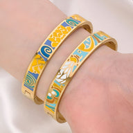 Bracelets joncs dorés émaillés multicolores avec motifs abstraits bleu, jaune et blanc.