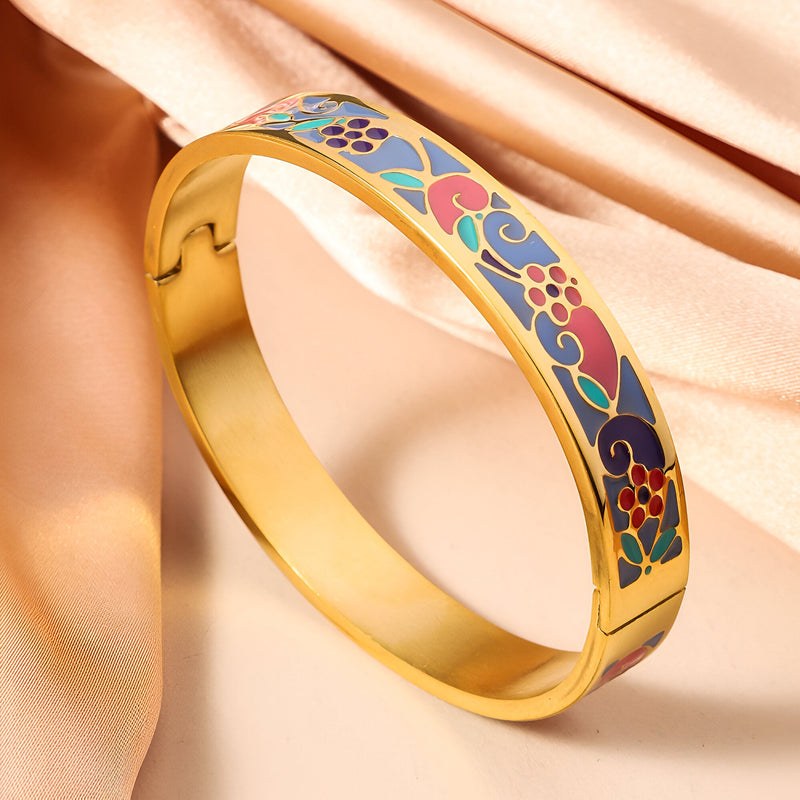 Bracelet jonc doré avec émail motifs floraux multicolores sur fond bleu et rouge.