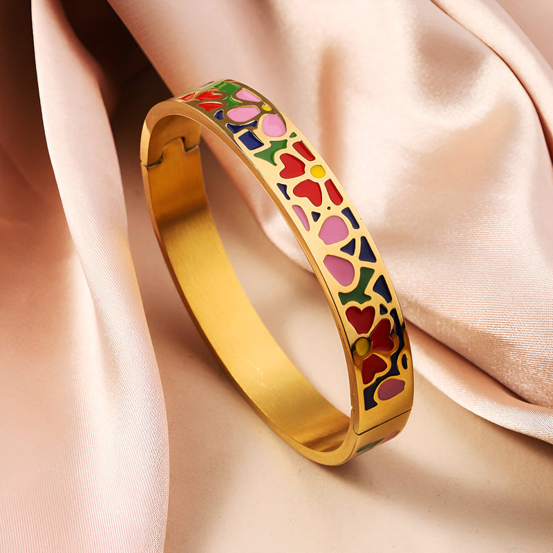 Bracelet jonc doré émaillé avec motifs floraux colorés rouges, roses et verts élégants.