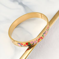 Bracelet jonc doré émaillé avec motifs floraux colorés rouges et roses pour femme.