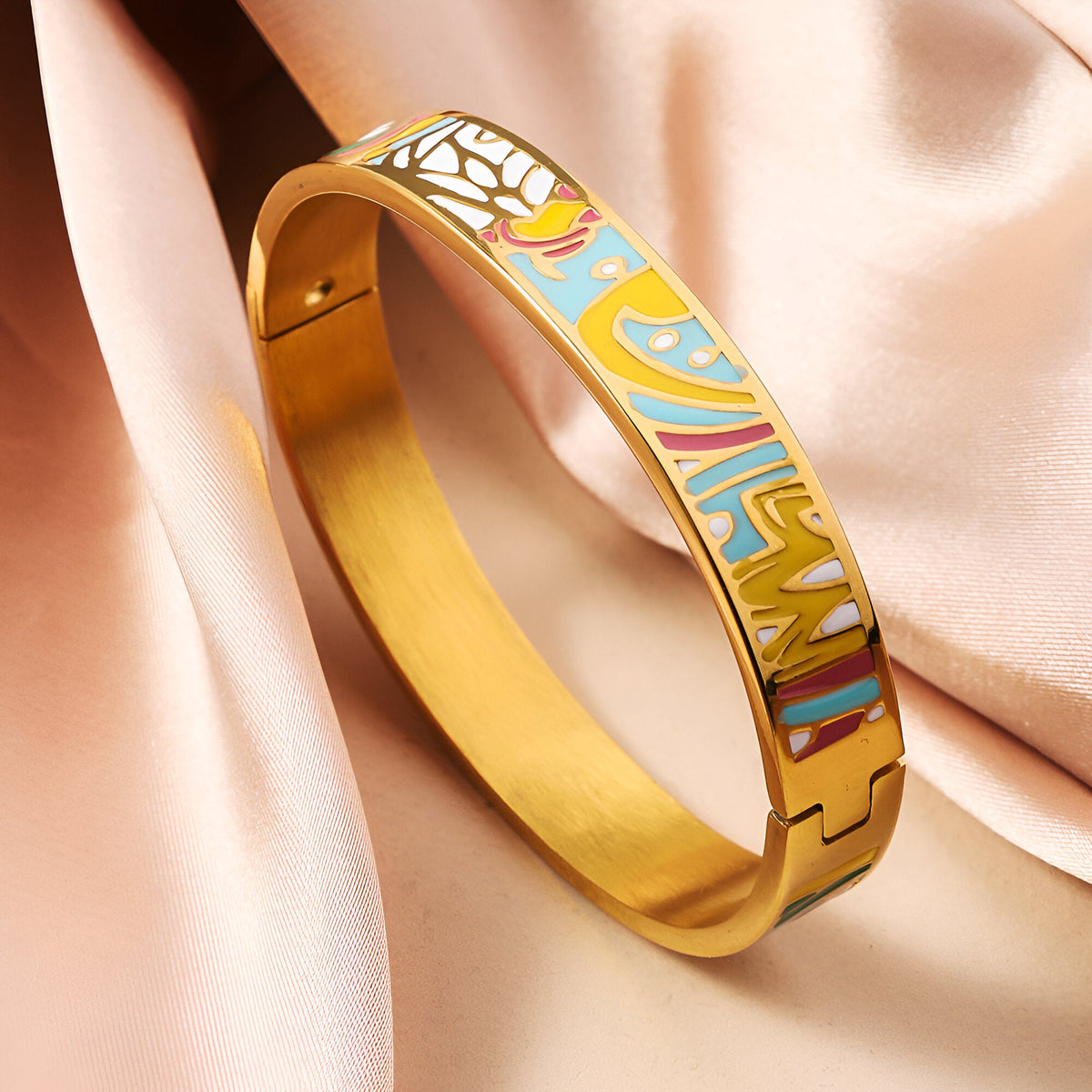 Bracelet jonc doré avec émail bleu, blanc et jaune, motifs floraux délicats, fermoir invisible.