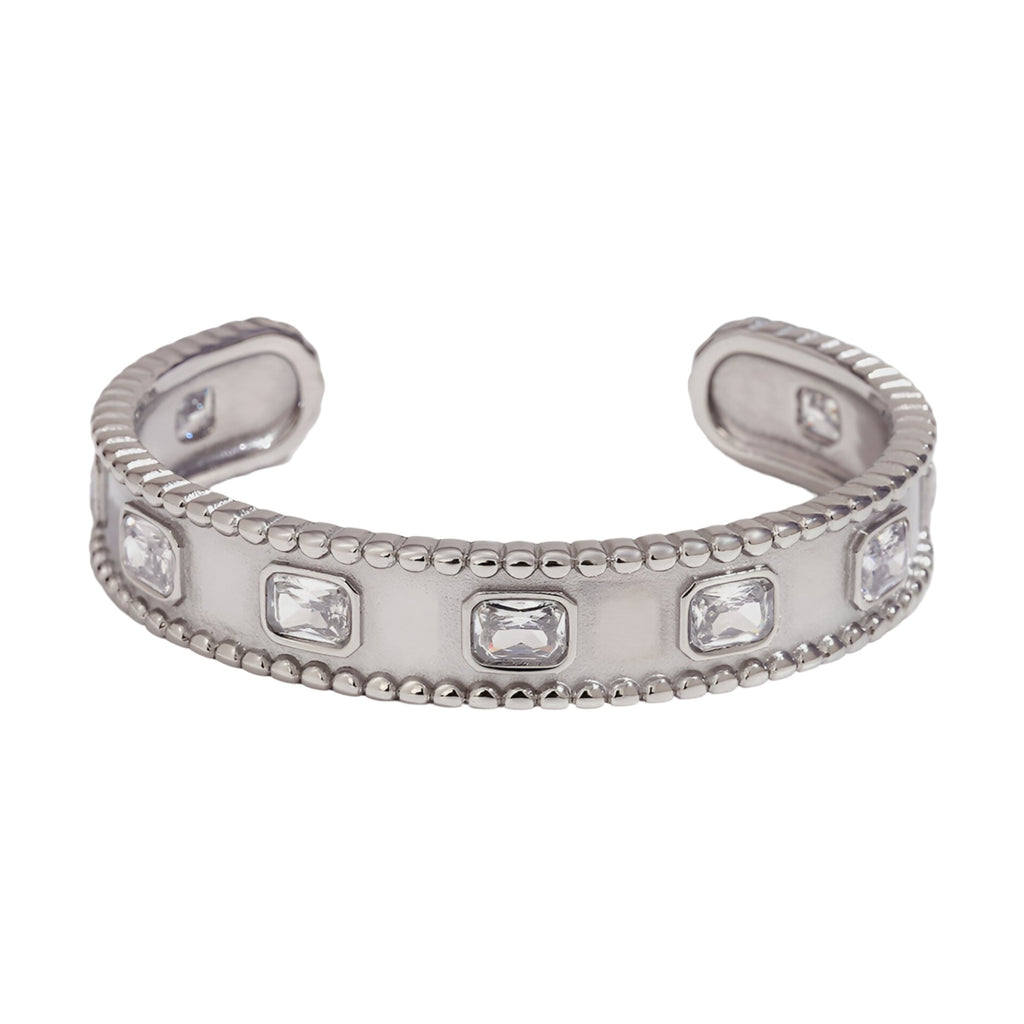 Bracelet jonc argenté en acier inoxydable avec pierres rectangulaires serties et bords perlés.