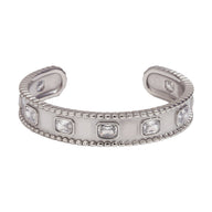 Bracelet jonc argenté en acier inoxydable avec pierres rectangulaires serties et bords perlés.