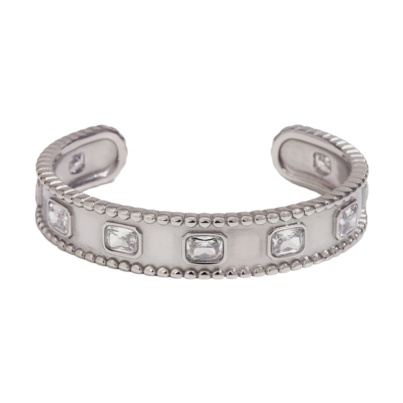 Bracelet jonc argenté en acier inoxydable avec pierres rectangulaires serties et bords perlés.