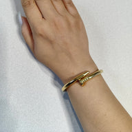 Bracelet jonc en acier inoxydable finition or, design clou moderne et épuré, porté au poignet féminin.