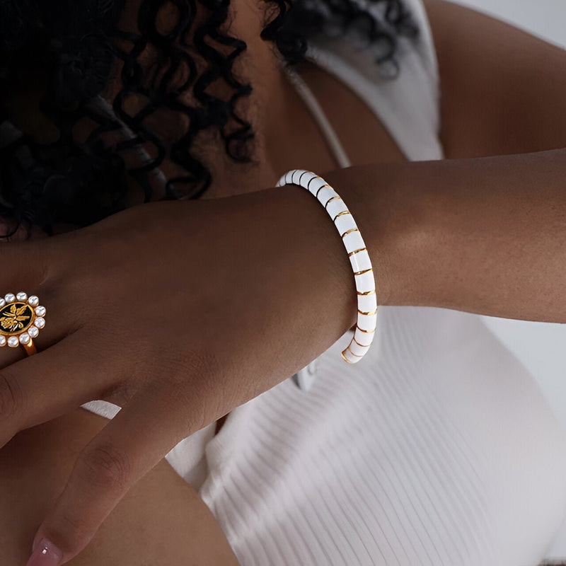 Bracelet jonc blanc en titane et acrylique aux maillons réguliers, porté au poignet féminin.