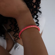 Bracelet jonc rose en titane et acrylique avec petits motifs dorés.