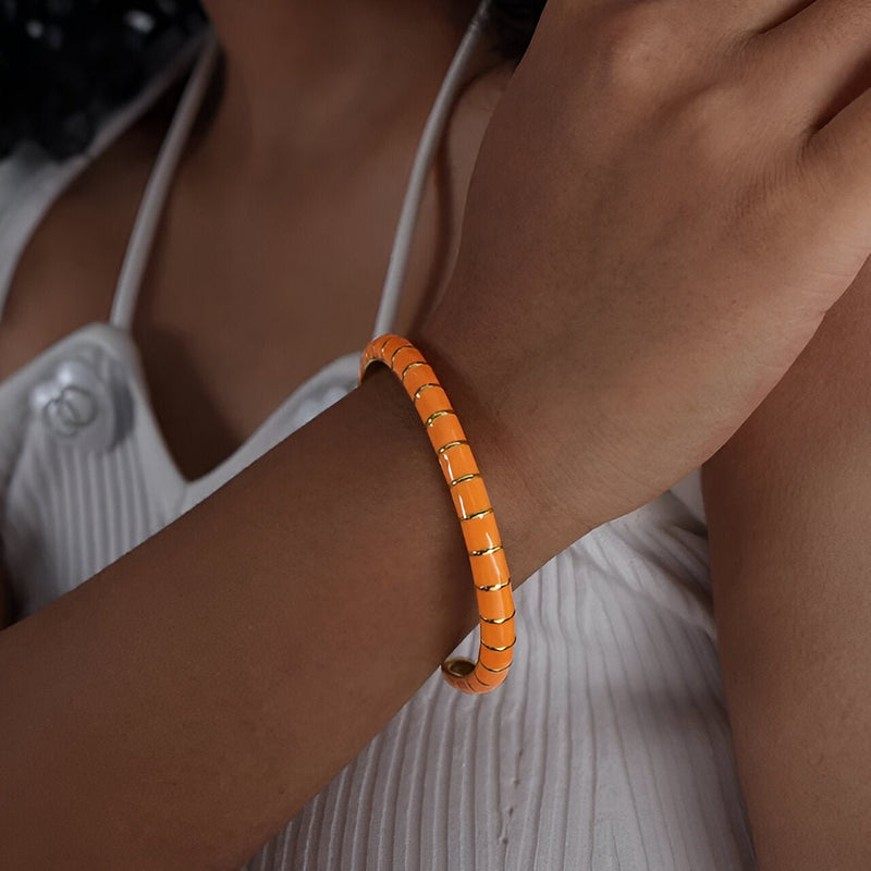 Bracelet jonc orange en titane et acrylique, design segmenté, porté au poignet féminin.