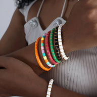 Bracelets joncs colorés en titane et acrylique, styles rose, vert, noir, blanc et multicolore, portés sur poignet féminin.