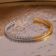 Bracelet jonc ouvert en acier inoxydable, moitié torsadé argenté, moitié lisse doré, style contemporain.