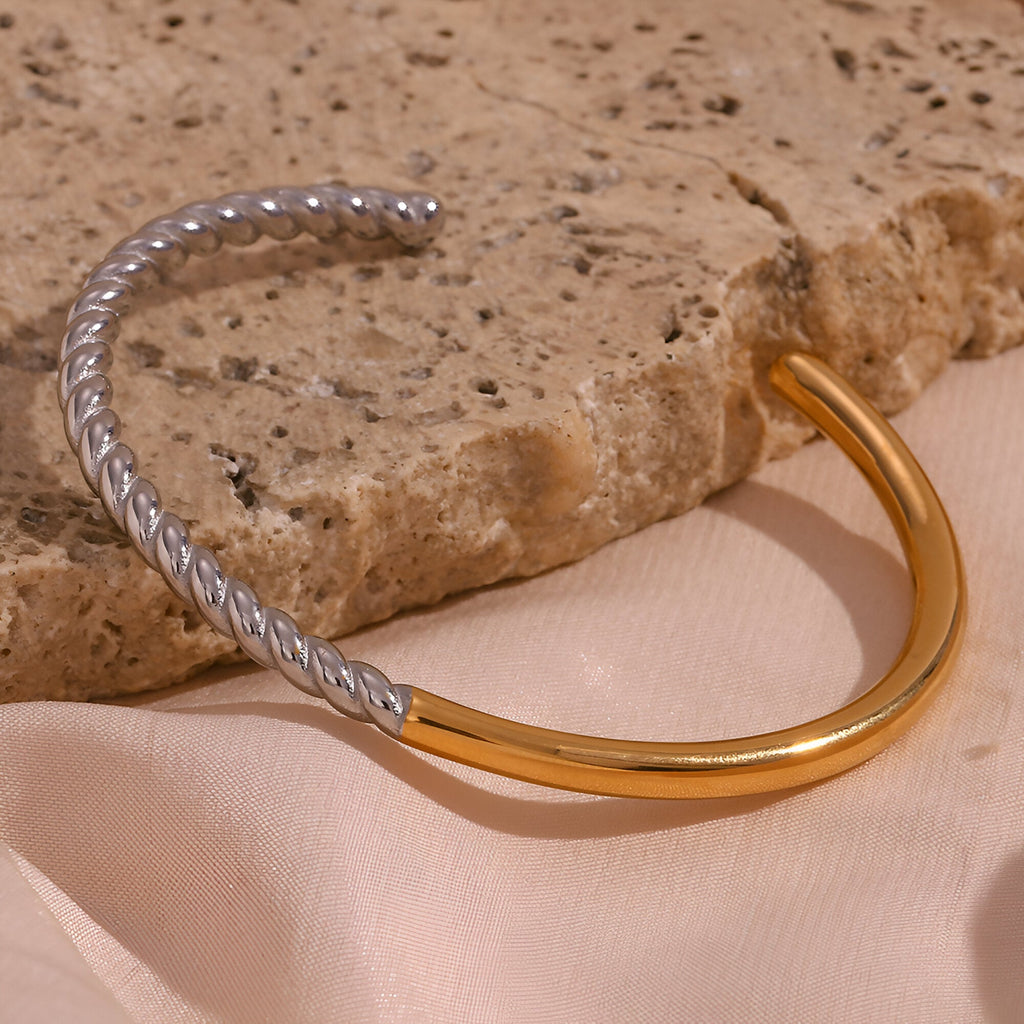Bracelet jonc en acier inoxydable, torsade argentée et partie lisse dorée, style contemporain.