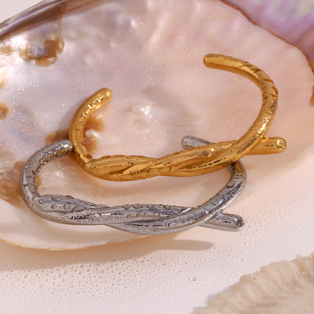 Bracelet jonc demi nœud en acier inoxydable or et argent avec texture gravée délicate.