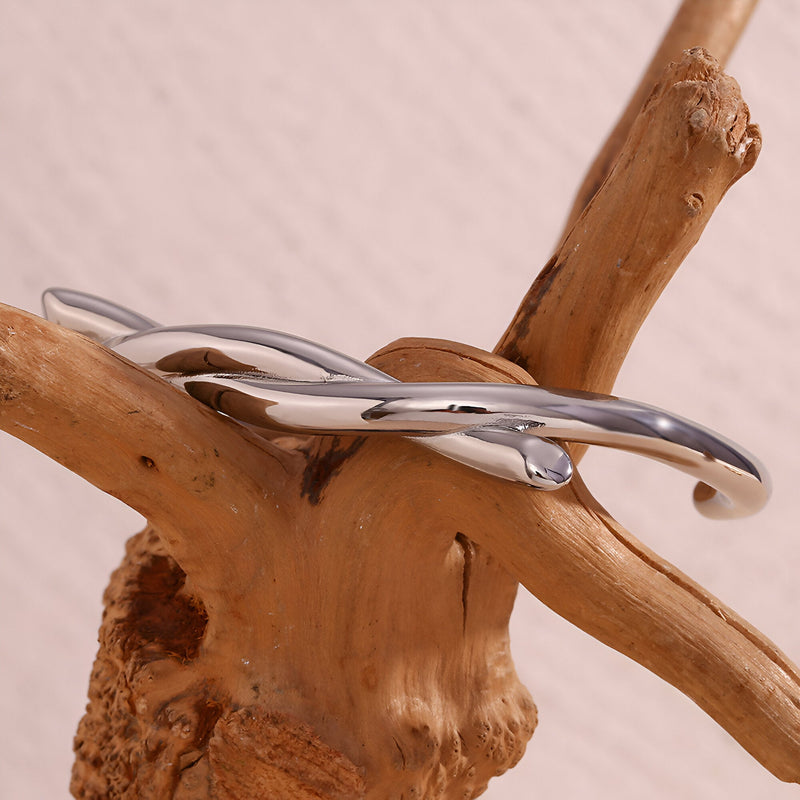 Bracelet jonc argenté en acier inoxydable avec demi-nœud lisse et finition brillante.